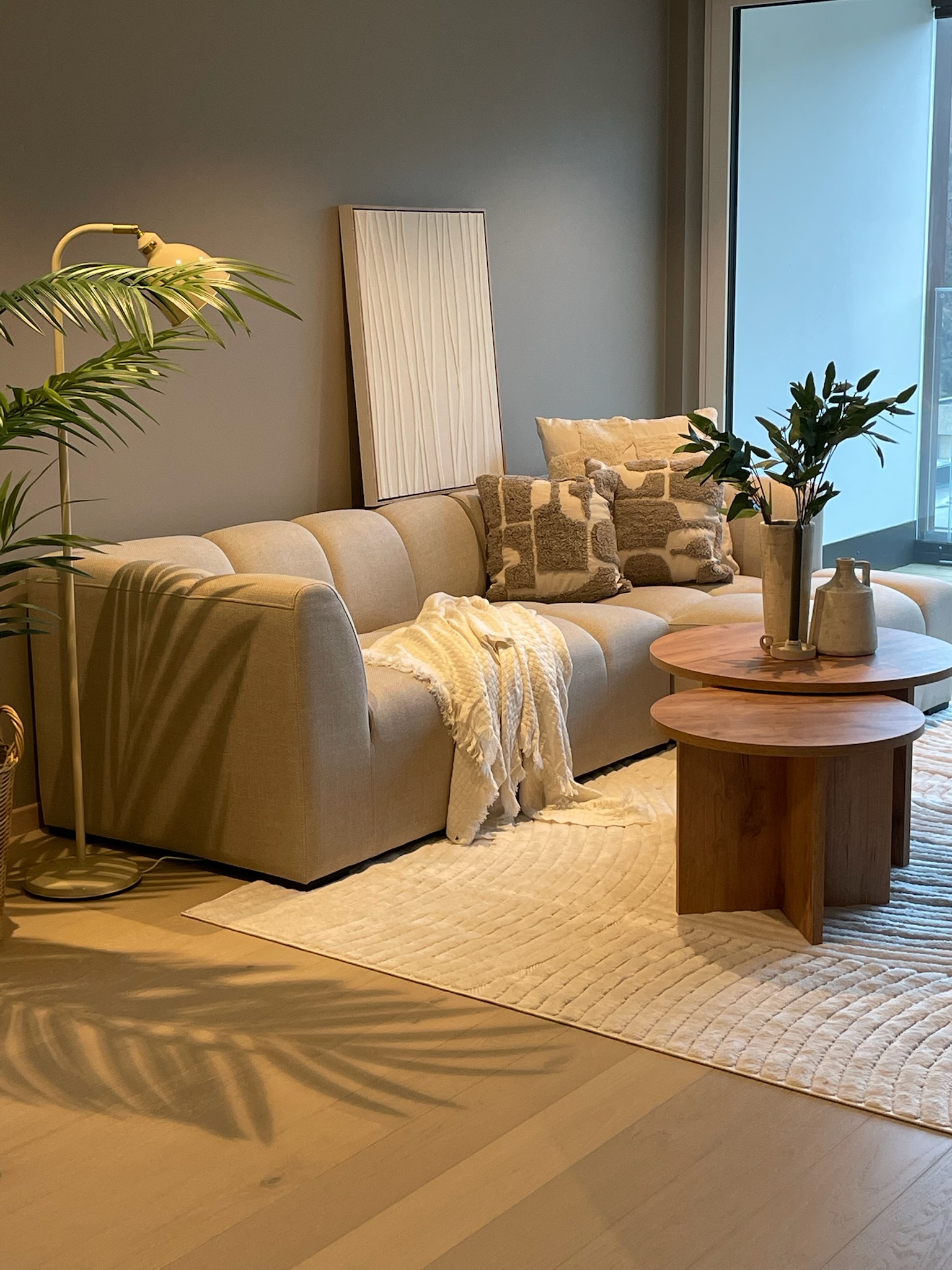 Boligstyling stue med beige sofa, tremøbler og planter